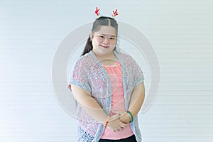 Portrait studio shot of Asian young cute chubby female down syndrome autistic model wear red dear antlers headband and casual