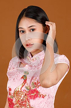 Portrait closeup studio shot millennial Asian female model in pink Chinese cheongsam qipao traditional peacock & flowers pattern