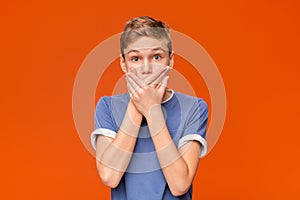 Portrait of stunned boy on orange studio background