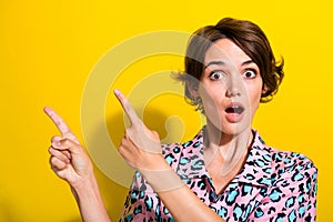 Portrait of stunned speechless person direct fingers empty space news ad isolated on yellow color background