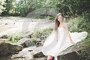 Portrait of stunning bride with long hair standing by the river