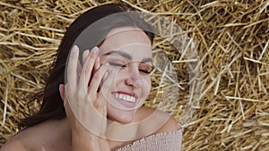 Portrait of stunning brunette laughing gently at camera on hay background