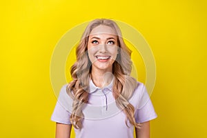 Portrait of stunning creative girl toothy smile look up above empty space blank isolated on yellow color background