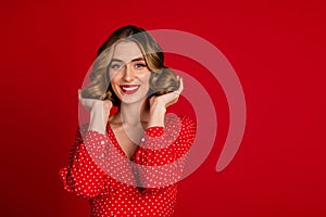 Portrait of stunning lovely girl toothy smile arms touch wavy hairdo empty space isolated on red color background