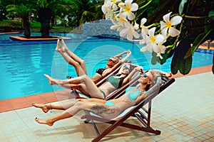 Portrait of stunning sexy women taking sunbaths on lounges, with legs up