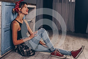 Portrait of a stunning smiling girl with red lips, dressed in a checkered red shirt and a bandana on her head. Model posing in