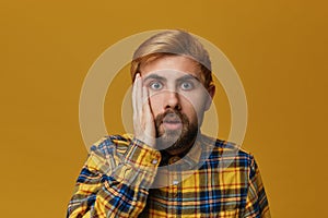 Portrait of stupefied bearded male, with dyed blond gold hair keeps mouth widely opened, wonders about something