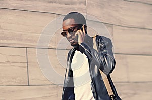 Portrait of stylish african man calling on smartphone walking on city street background