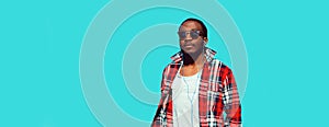 Portrait of stylish african man listens to music with earphones on blue background