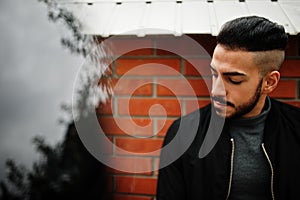 Portrait of stylish arab beard man wear grey turtleneck and black jaket. Arabian model guy against brick wall