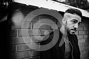 Portrait of stylish arab beard man wear grey turtleneck and black jaket. Arabian model guy against brick wall