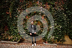 Portrait of stylish arab beard man wear grey turtleneck and black jaket. Arabian model guy on a background of autumn leaves