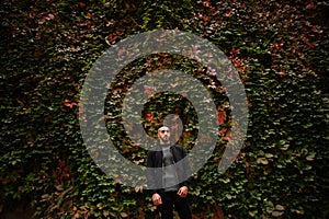 Portrait of stylish arab beard man wear grey turtleneck and black jaket. Arabian model guy on a background of autumn leaves