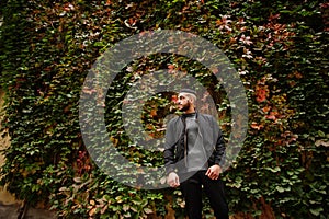 Portrait of stylish arab beard man wear grey turtleneck and black jaket. Arabian model guy on a background of autumn leaves