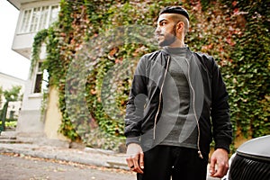 Portrait of stylish arab beard man wear grey turtleneck and black jaket. Arabian model guy on a background of autumn leaves