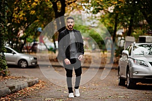 Portrait of stylish arab beard man wear grey turtleneck and black jaket. Arabian model guy on a background of autumn leaves