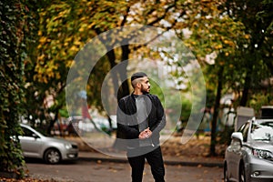 Portrait of stylish arab beard man wear grey turtleneck and black jaket. Arabian model guy on a background of autumn leaves