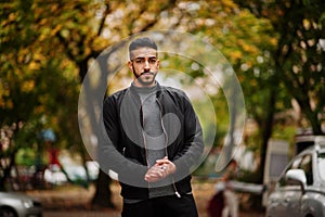 Portrait of stylish arab beard man wear grey turtleneck and black jaket. Arabian model guy on a background of autumn leaves