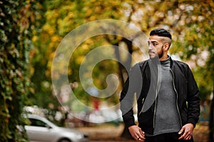 Portrait of stylish arab beard man wear grey turtleneck and black jaket. Arabian model guy on a background of autumn leaves