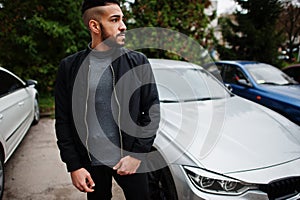 Portrait of stylish arab beard man wear grey turtleneck and black jaket. Arabian model guy stand near his car