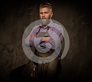 Portrait of stylish barber with beard and professional tools isolated on a dark background.