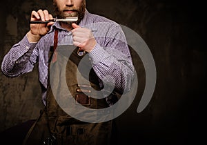 Portrait of stylish barber with beard and professional tools isolated on a dark background.
