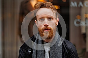 Portrait of a stylish bearded man against the background of elegant clothing store window.