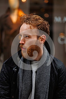 Portrait of a stylish bearded man against the background of elegant clothing store window.