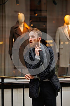 Portrait of a stylish bearded man against the background of elegant clothing store window.