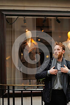 Portrait of a stylish bearded man against the background of elegant clothing store window.