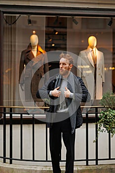 Portrait of a stylish bearded man against the background of elegant clothing store window.