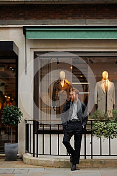 Portrait of a stylish bearded man against the background of elegant clothing store window