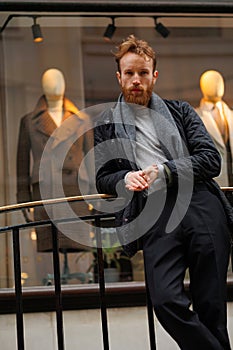 Portrait of a stylish bearded man against the background of elegant clothing store window.