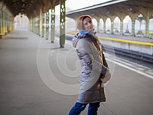 Portrait of a stylish beautiful woman with red hair under the clock at the Vitebsk train station in St. Petersburg, Russia