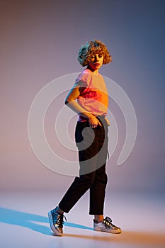 Portrait of stylish beautiful young redheaded woman posing isolated on dark studio background in neon. Human emotions