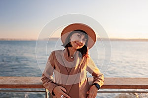 Portrait of a stylish and beautiful young woman in a coat and hat. Walk along the embankment. Autumn near the sea