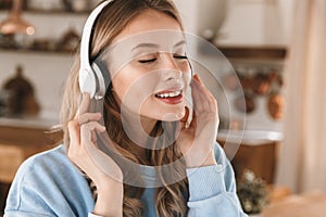 Portrait of stylish blond girl 20s wearing headphones listening to music at home