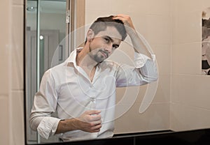 Portrait of stylish cheerful glad happy handsome cheerful young man combing his hair and laugh. Man take care about his hair. A ma
