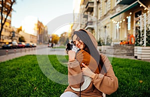 Portrait of a stylish dog-owner female hugging her little yorkshire terrier, wearing a fashionable hoodie, sitting on the green