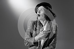 Portrait of stylish emotive woman in classical clothes, jacket and hat showing emotions of shock. Black and white
