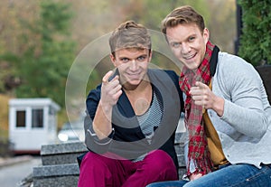 Portrait of stylish fashionable twin brothers sitting on the sta
