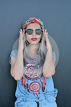 Portrait of stylish glamorous young woman posing on grey background wearing big black sunglasses