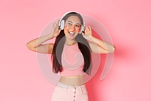 Portrait of stylish good-looking asian girl enjoying listening music in headphones, looking dreamy and upbeat with
