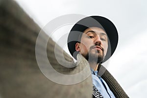 Portrait of a stylish handsome young man face wearing a coat outdoors. Low angle view of a man wearing a coat and a scarf looking