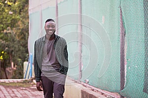 Portrait of stylish happy african american man on sportswear,green shirt walking. Black men model street fashion.