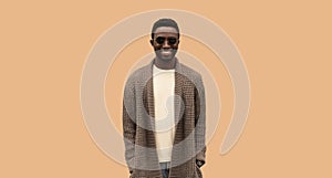 Portrait of stylish happy smiling young african man wearing knitted cardigan isolated on brown background