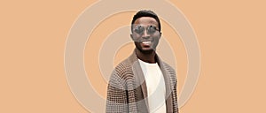 Portrait of stylish happy smiling young african man wearing knitted cardigan isolated on brown background