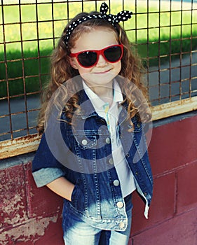 Portrait stylish little girl child wearing a jeans clothes posing in the city