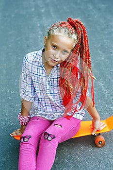 Portrait of a stylish little girl with a skateboard .