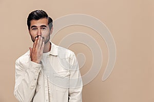 Portrait of a stylish male fashion model on a beige background in a white t-shirt looks at the camera, trendy clothing